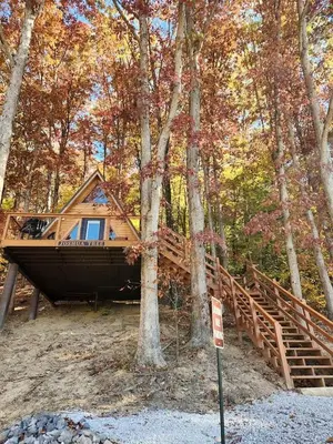a cabin in the woods with a sign in front of it at Rustic Tree A-Frame with Original Design by Tappan Lake in Ohio in Deersville