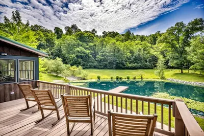 a deck with chairs and a pond at Cozy Secluded Cabin with Games and Hot-tub in Sarahsville, Ohio