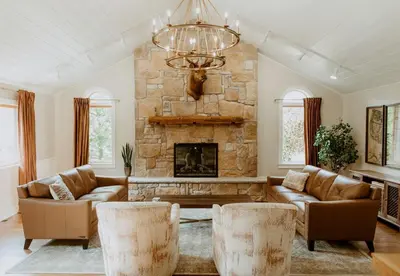 a living room with couches and a stone fireplace at 16 Guests | Ponds | Hot Tub | Game Room | Trails in Sarahsville