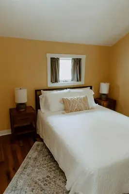 a bedroom with a large white bed with two night stands at 16 Guests | Ponds | Hot Tub | Game Room | Trails in Sarahsville