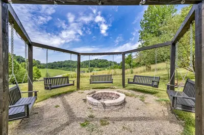 a group of benches sitting around a fire pit at Exquisite Cabin with Amazing Interior and Exterior in Sarahsville, Ohio