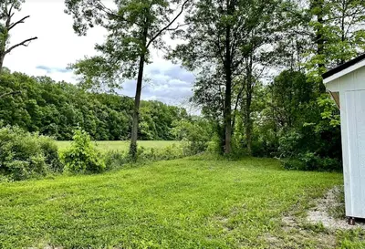 an empty yard with trees and a white house at Charming Cabin Surrounded by Woods and Fields in Oberlin, Ohio in Oberlin