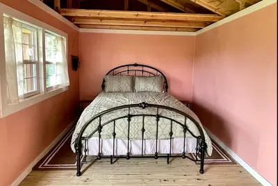 a bed in a room with a pink wall at Cozy Cabin Surrounded by Fields and Woods in Oberlin, Ohio in Oberlin