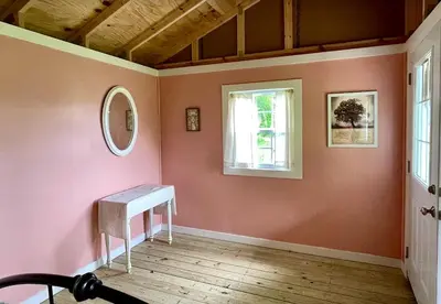 a room with a pink wall with a bench and a window at Cozy Cabin Surrounded by Fields and Woods in Oberlin, Ohio in Oberlin