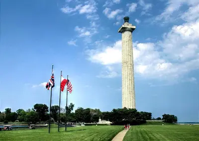 a tall tower with american flags in a field at Spacious Vacation Cottage Rental near the Waterfront in Beautiful Put-in-Bay, Ohio in Put-in-Bay