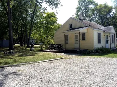 a small yellow house with a gravel driveway at Enchanting Cottage Rental in Marblehead, Ohio in Marblehead