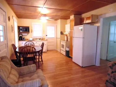 a kitchen with a table and a white refrigerator at Enchanting Cottage Rental in Marblehead, Ohio in Marblehead