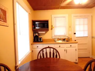 a kitchen with a table and a sink and a microwave at Enchanting Cottage Rental in Marblehead, Ohio in Marblehead