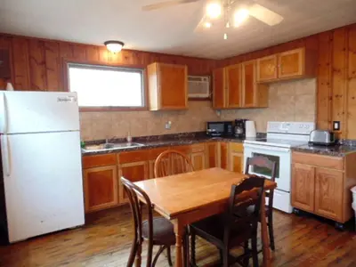 a kitchen with a table and a white refrigerator at Secluded Cottage Rental in the Trees by Lake Erie, Ohio in Marblehead