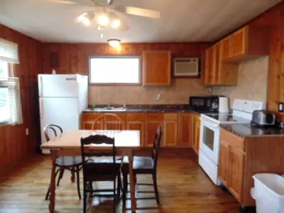 a kitchen with a table and a white refrigerator at Secluded Cottage Rental in the Trees by Lake Erie, Ohio in Marblehead