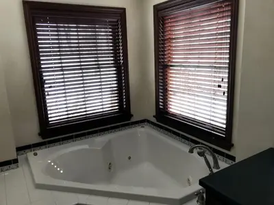 a bath tub in a bathroom with two windows at Enchanting Vacation Rental with a Private Fishing Stream in Sandusky, Ohio in Sandusky