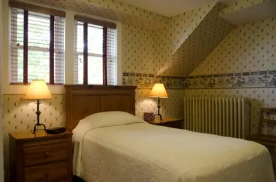 a bedroom with a bed and two lamps and two windows at Inviting Suite Rental in a Charming Farmhouse in Sandusky, Ohio in Sandusky