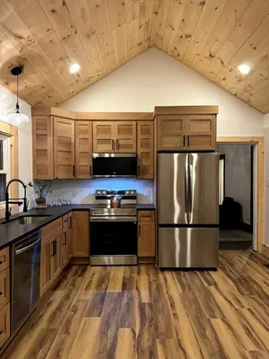 a kitchen with wooden cabinets and a stainless steel refrigerator at 1800s Farmhouse Cottage Rental on a 230 Acre Farm in Muskingum County, Ohio in Frazeysburg