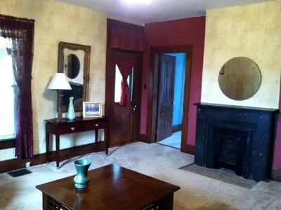 a living room with a fireplace and a table at 1800s Farmhouse Cottage Rental on a 230 Acre Farm in Muskingum County, Ohio in Frazeysburg