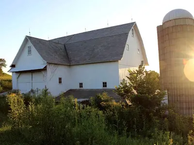a large white barn with a silo and a silo at 1800s Farmhouse Cottage Rental on a 230 Acre Farm in Muskingum County, Ohio in Frazeysburg