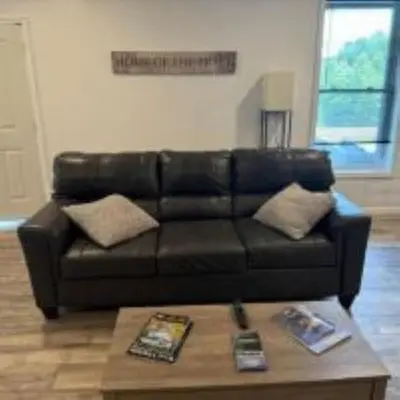 a black leather couch in a living room with a coffee table at The Murphy in Sutton
