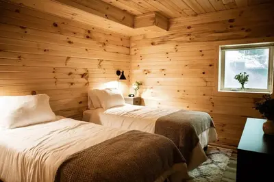 two beds in a room with wooden walls at The Oak at Middlefork Ridge in Laurelville
