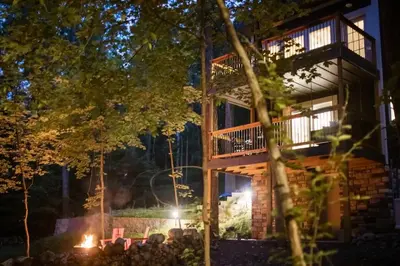 a group of people sitting around a fire in front of a building at The Acorn at Middlefork Ridge in Laurelville