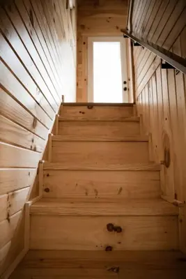 a staircase in a wooden cabin with a window at The Acorn at Middlefork Ridge in Laurelville