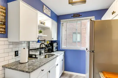 a kitchen with blue walls and white cabinets and a refrigerator at 1 Mi to University of Cincinnati Avondale Gem! in Cincinnati