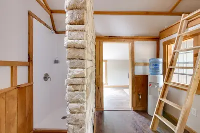 a room with a stone wall and a ladder at Cabin with Trail Access to Mohican River in Brinkhaven