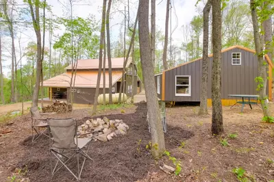 a tiny house in the woods with two chairs and a tent at Cabin with Trail Access to Mohican River in Brinkhaven
