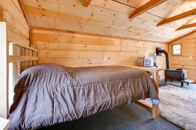 a bedroom with a bed in a log cabin at On-Site Trails to Mohican River Tiny Home Retreat in Brinkhaven