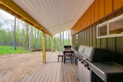 a covered porch with a stove and a table and chairs at 1 Mi to Mohican River Wooded Retreat with Trails! in Brinkhaven