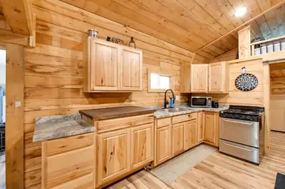 a kitchen with wooden cabinets and a stove at 1 Mi to Mohican River Wooded Retreat with Trails! in Brinkhaven