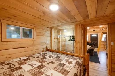 a bedroom with a bed in a wooden cabin at 1 Mi to Mohican River Wooded Retreat with Trails! in Brinkhaven