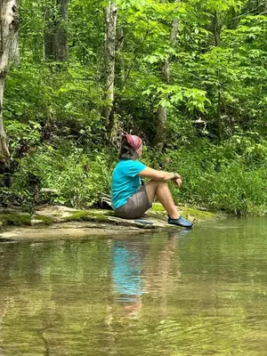 a woman sitting on the edge of a body of water at Magical Family Tree House in Secluded Woodland near Germantown, Kentucky in Germantown