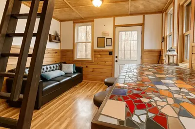 a living room with a couch and a table at Enchanting Tree House with a Slide on 200 Acres for a Family Adventure in Germantown, Kentucky in Germantown
