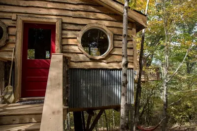 a small log cabin with a red door at Stunning Tree House Tucked Away Among the Trees near Germantown, Kentucky in Germantown