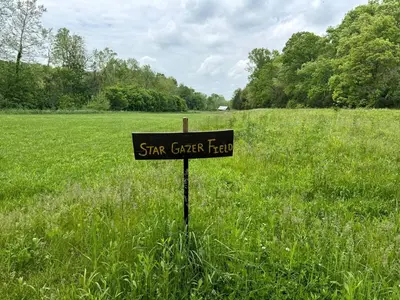a sign in the middle of a grass field at Stunning Tree House Tucked Away Among the Trees near Germantown, Kentucky in Germantown