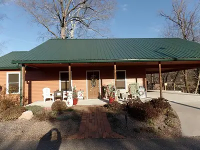 a small house with a green roof and chairs at Woodland Cottage Rental Perfect for Couples Overlooking Raccoon Creek in Ohio in Bidwell