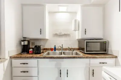 a white kitchen with a sink and a microwave at OSU - Heart of Short North -STEPS from High ST-OSU in Columbus