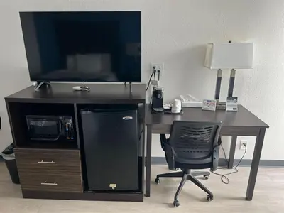 a desk with a computer and a chair and a television at Travelodge by Wyndham Gallipolis in Gallipolis