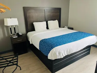 a bedroom with a large bed with a blue blanket at Travelodge by Wyndham Gallipolis in Gallipolis