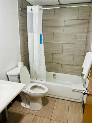 a bathroom with a toilet and a tub and a sink at Travelodge by Wyndham Gallipolis in Gallipolis