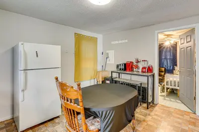 a kitchen with a table and a refrigerator at 3 Mi to Dtwn Fort Wayne Home with Deck and Yard! in Fort Wayne