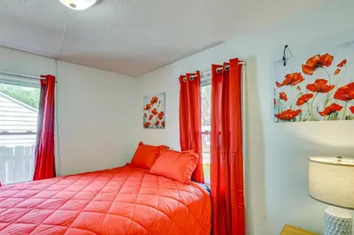 a bedroom with a bed with red curtains and a window at 3 Mi to Dtwn Fort Wayne Home with Deck and Yard! in Fort Wayne
