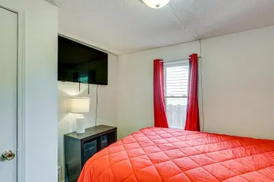 a bedroom with a red bed and a window at 3 Mi to Dtwn Fort Wayne Home with Deck and Yard! in Fort Wayne