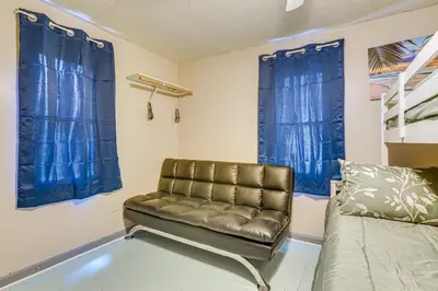 a living room with a couch and blue curtains at 3 Mi to Dtwn Fort Wayne Home with Deck and Yard! in Fort Wayne