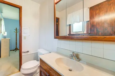 a bathroom with a sink and a toilet and a mirror at 8 Mi to Cleveland Family Home with Fenced Backyard! in Brooklyn
