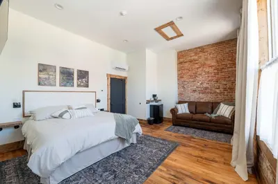 a bedroom with a bed and a brick wall at Courthouse Suite - Room 1 in Versailles