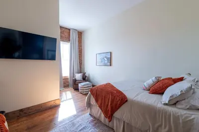 a bedroom with a bed and a flat screen tv at Courtyard Queen - Room 2 in Versailles
