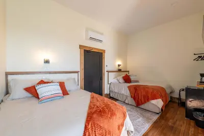 a bedroom with two beds with orange and blue pillows at Courtyard Queen - Room 2 in Versailles