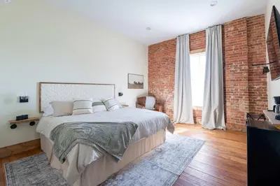 a bedroom with a large bed and a brick wall at Courtyard King - Room 3 in Versailles