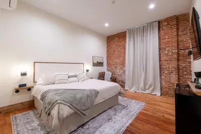 a bedroom with a large bed and a brick wall at Courtyard King - Room 3 in Versailles