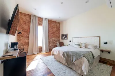 a bedroom with a bed and a brick wall at Courtyard King - Room 4 in Versailles